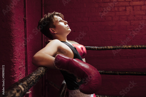 Young boxer taking a break on the ring during training to get his breath back