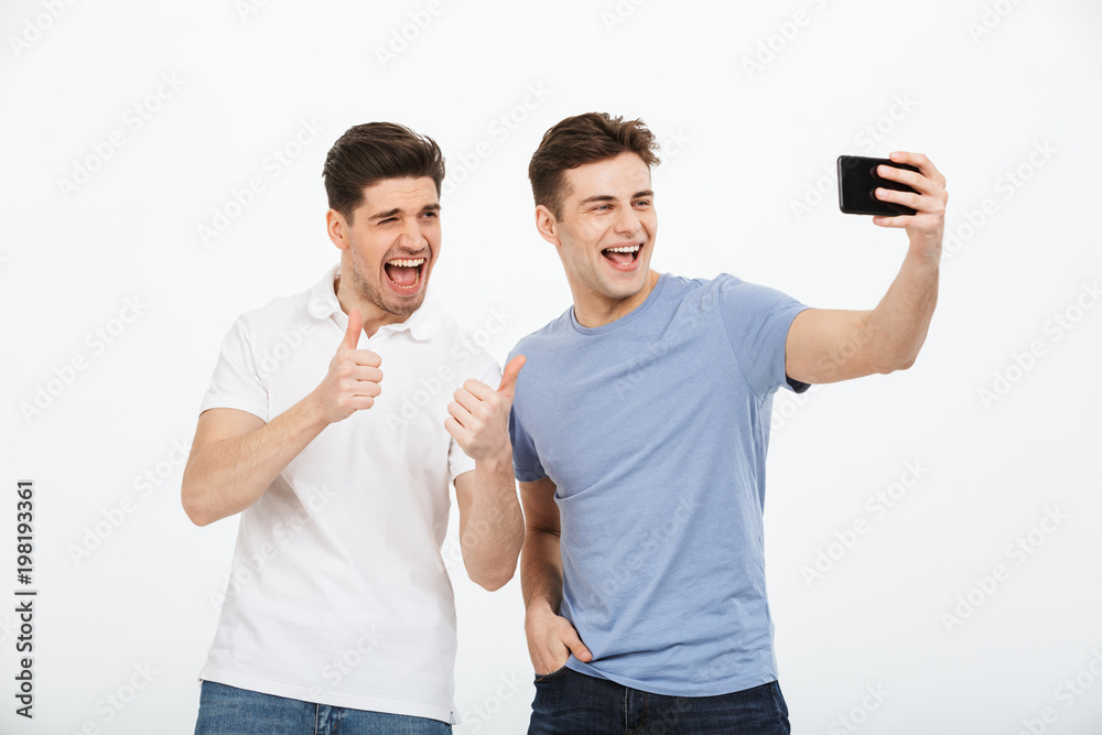Portrait of two happy young men pointing finger Portrait of two happy young men pointing finger