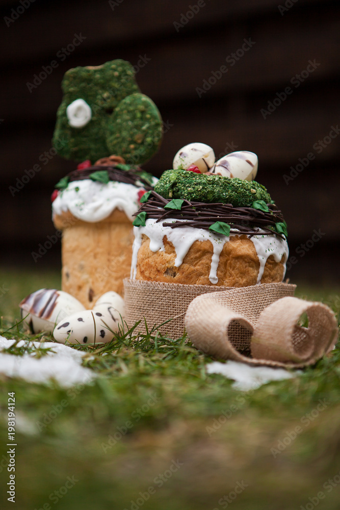 Easter cake in eco-style decorated with chocolate eggs in a nest on the background of spring grass and snow Easter cake in eco-style decorated with chocolate eggs in a nest on the background of spring grass and snow