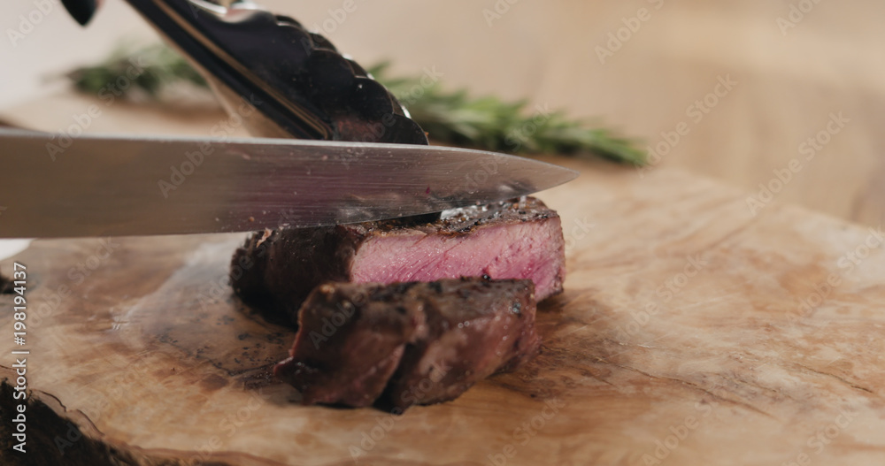 slicing medium rare fillet mignon steak on wood board slicing medium rare fillet mignon steak on wood board
