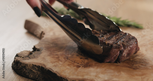 slicing medium rare fillet mignon steak on wood board
