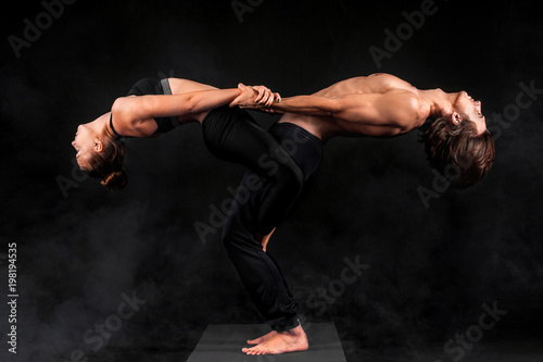 Acroyoga. Young couple practicing acro yoga on mat in studio together. Couple yoga. Partner yoga. Black and white photo. photo