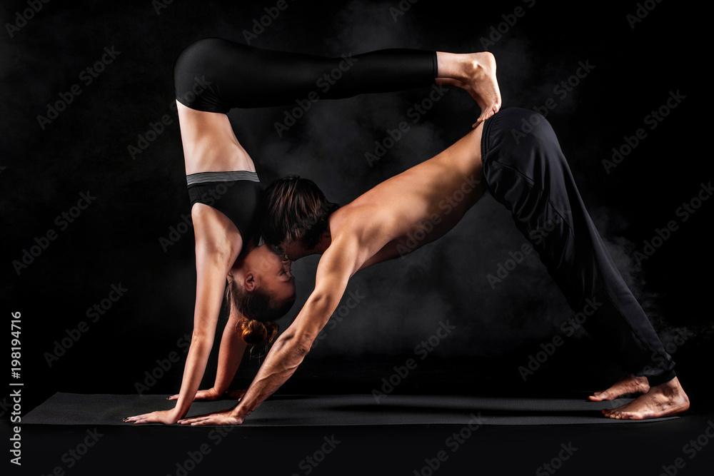Acroyoga. Young couple practicing acro yoga on mat in studio together. Couple yoga. Partner yoga. Black and white photo.