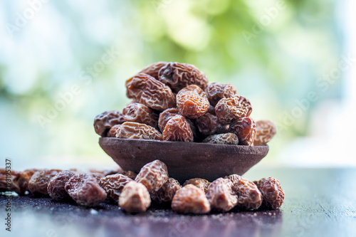 Close up of raw dried dates,Phoenix dactylifera in a traditional bowl on a wooden surface. photo