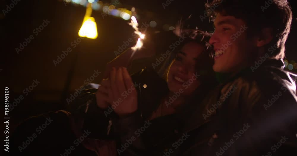 Young couple with sparkler flirting during late night date Young couple with sparkler flirting during late night date