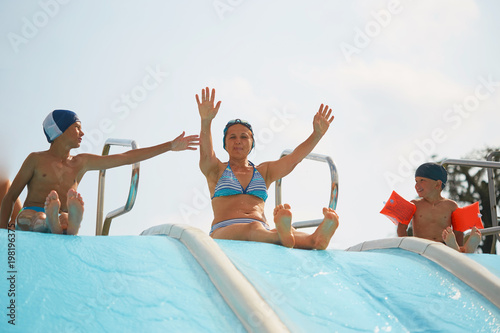 child in armlets for swimming in an outdoor pool with a water slide.