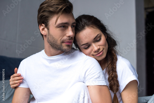 Young man and woman tenderly embracing in bedroom