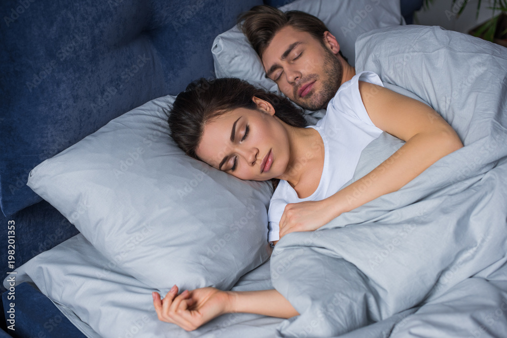 Young attractive couple hugging while sleeping in bed Young attractive couple hugging while sleeping in bed