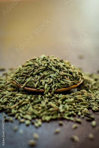 Raw dried fennel seeds or variyali or Foeniculum vulgare in a brown plate on wooden surface. photo