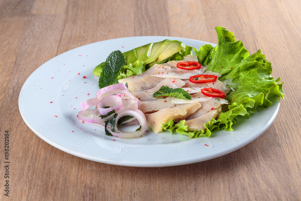 1. herring fillet with onion, chili pepper and avocado is laid out on a leaf of green salad 1. herring fillet with onion, chili pepper and avocado is laid out on a leaf of green salad