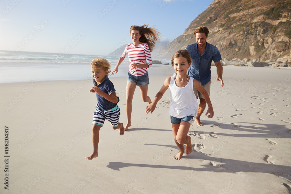 Parents Running Along Beach With Children On Summer Vacation Parents Running Along Beach With Children On Summer Vacation