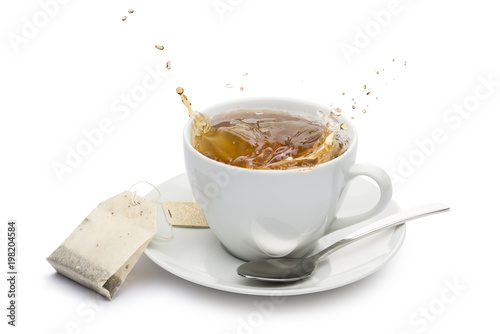 cup of tea with splashing and tea bag on white background photo