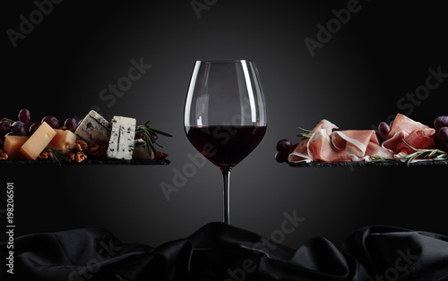 Glass of red wine with various cheeses , fruits and prosciutto .