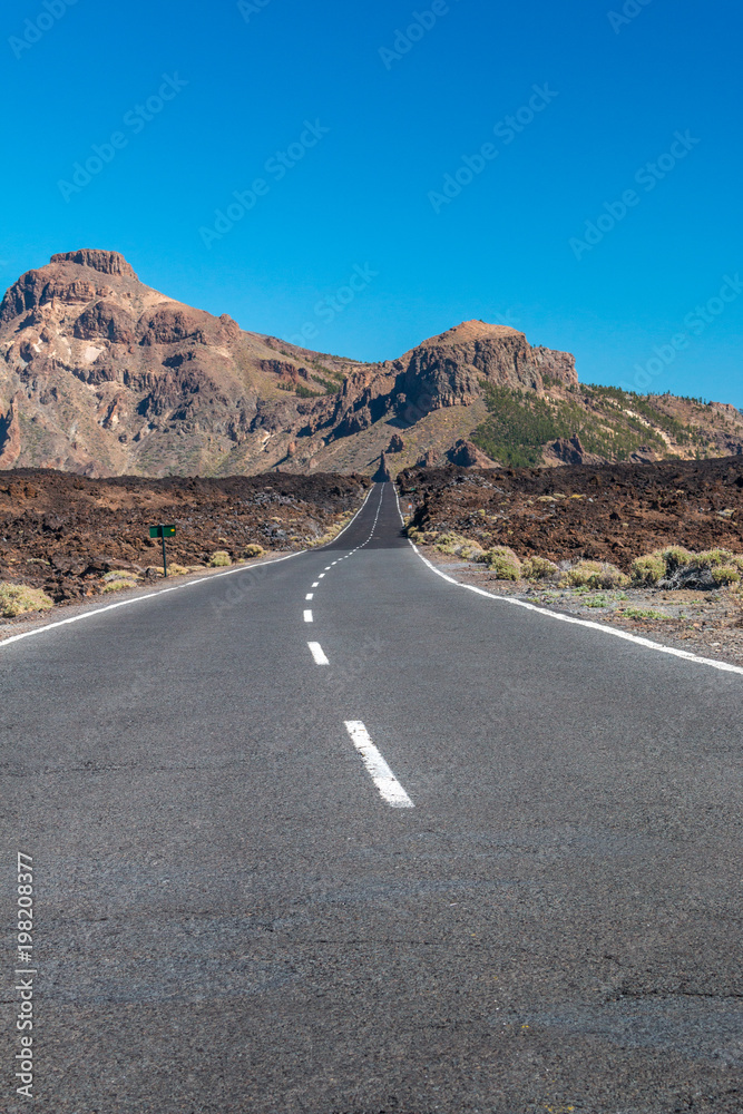 Straße durch Felder von erstarrter Lava, die zu den Bergen führt