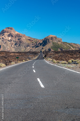 Straße durch Felder von erstarrter Lava, die zu den Bergen führt