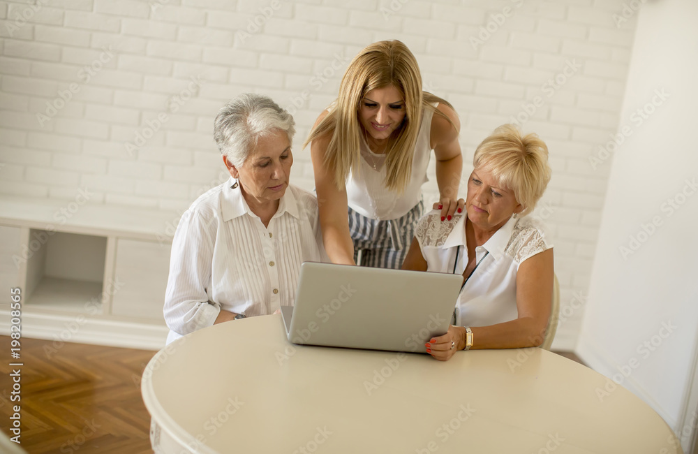 Happy women of three generations using laptop in the room at home Happy women of three generations using laptop in the room at home