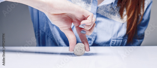 Woman spinning a coin to make decision. Heads or tails game. (chance, opportunity, fortune, luck concept) photo