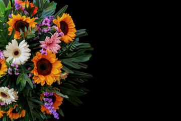 Sunflowers and Gerbera daisies flower arrangement with fern, philodendron and palm leaves the tropical foliage plants on black background.