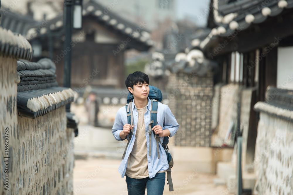 A young man doing a backpacking trip in a Korean traditional house.