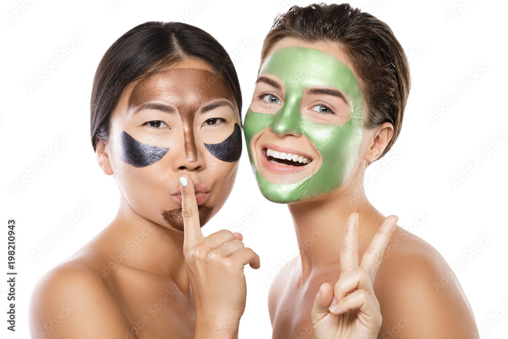 Two beautiful girls with colorful peel-off masks on their faces Two beautiful girls with colorful peel-off masks on their faces