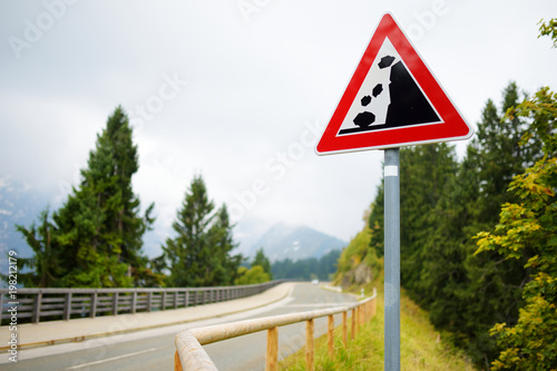 Falling rocks road sign on winding road in German Alps. Warning road sign in the mountains.