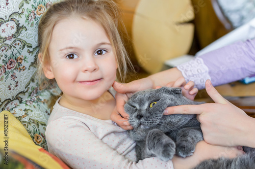 Close-up portrait of cat being hugged by child. Pet with strained smile . Kitten patience. Best friends. Pet care