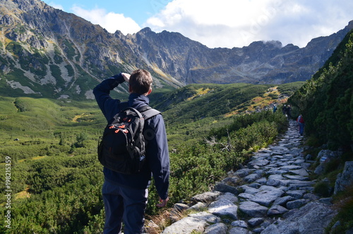Turysta górski patrzący na grań Orlej Perci ze szlaku niebieskiego do czarnego Stawu Gąsienicowego