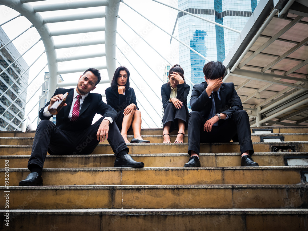 Group of business man and woman sitting in outdoors park and stressed because of business work failure Group of business man and woman sitting in outdoors park and stressed because of business work failure