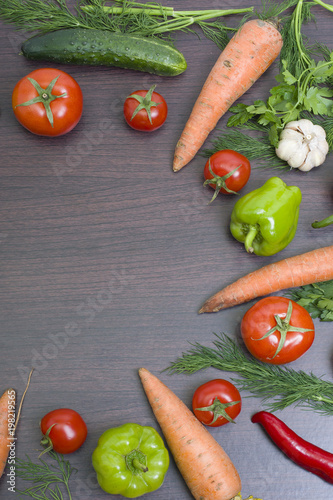 Vegetables concept on a wooden background. Carrots with green and red pepper on the table. Fresh vegetables on a brown wooden background.