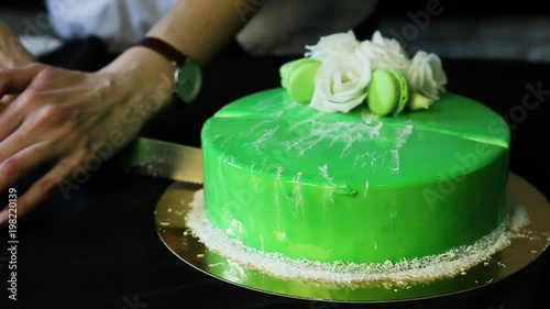 confectioner hands cut down whole reen cake in two parts photo