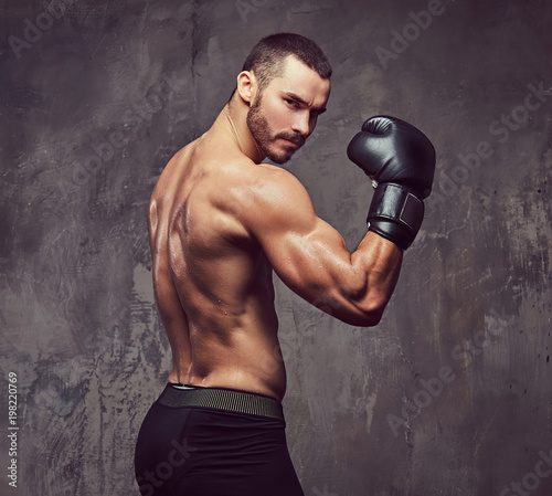 A brutal muscular boxer with boxing gloves working on punching technique. © Fxquadro