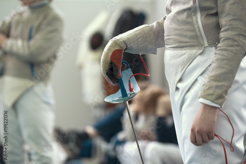 Young fencer holding rapier in his hand on the fencing tournament