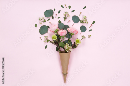 Top view of floral composition of beautiful pink rose flower in kraft cornet ...