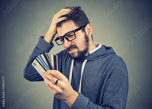 stressed man looking at too many credit cards photo