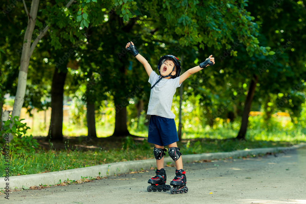 Little boy riding on rollers in the summer in the Park. Happy child in helmet learning to skate. Victory in the competition.