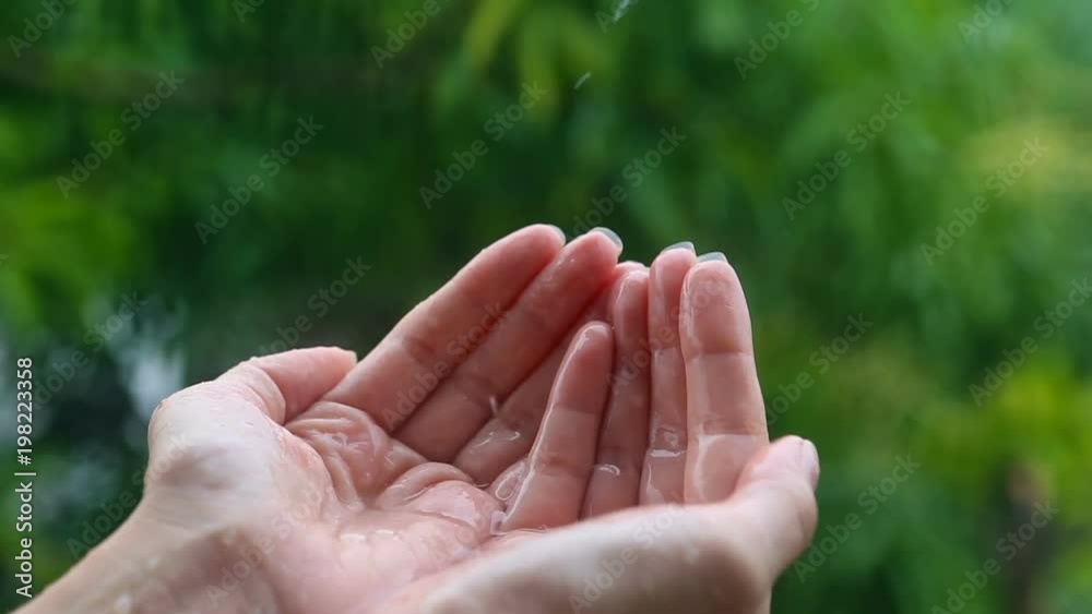 Hand under the rain, rainwater close-up. Woman putting her hand out to feel raindrops on her palm. Hand under the rain, rainwater close-up. Woman putting her hand out to feel raindrops on her palm.