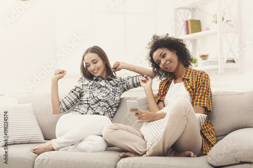 Two women listening to music and sharing earphones