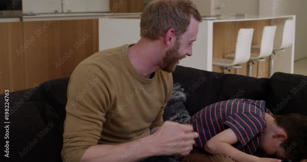 Father and son play games console in contemporary modern home, father is winning, in slow mo Father and son play games console in contemporary modern home, father is winning, in slow mo