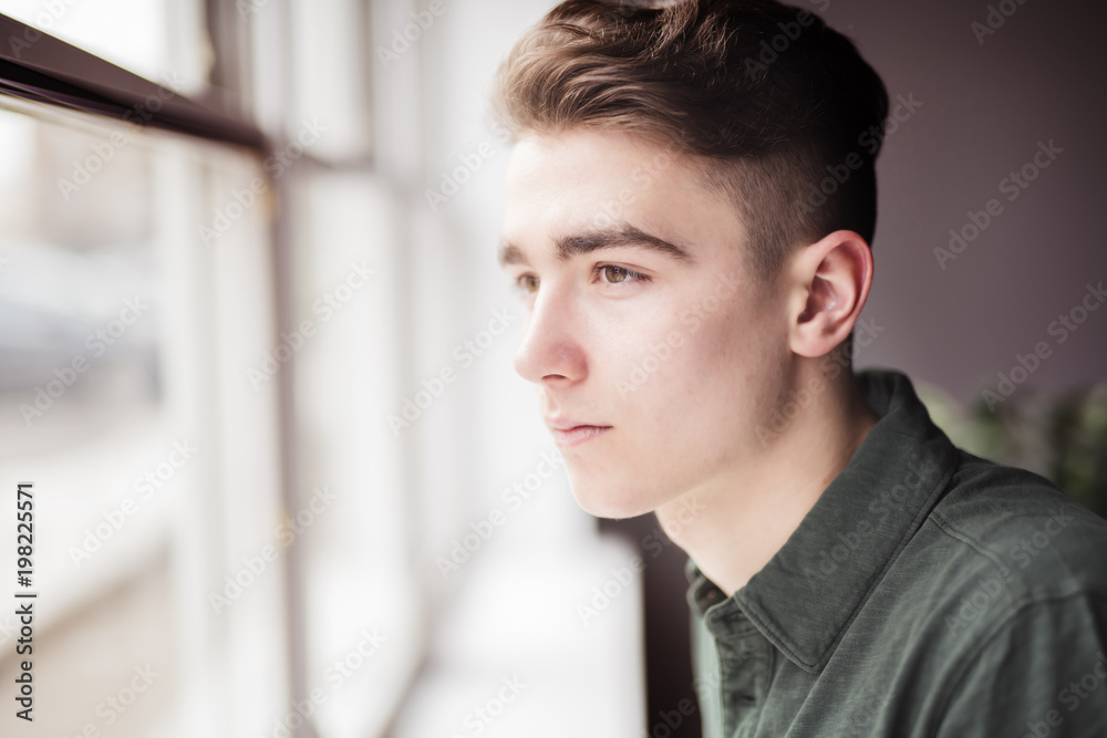 Man close to a window looking sad Man close to a window looking sad