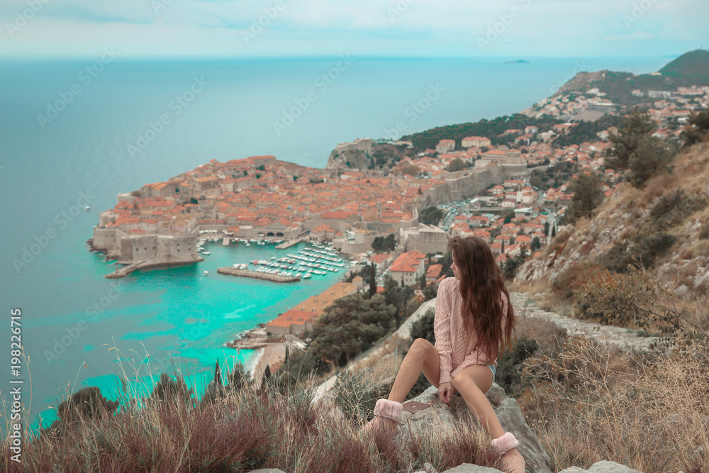 Brunette Girl tourist visiting mountain viewpoint  sightseeing in Dubrovnik, Croatia. Woman traveller in front on famous travel destination. Free brunette  enjoying vacation.