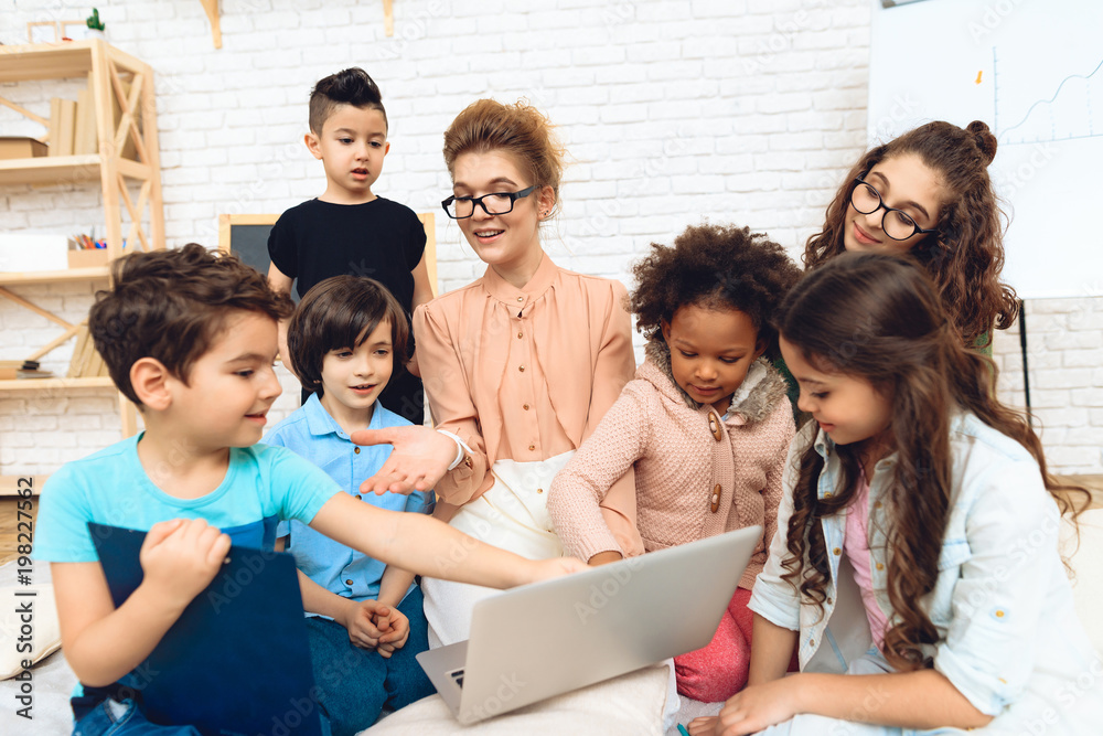 Group of children together with teacher are studying how to work with laptop. Group of children together with teacher are studying how to work with laptop.