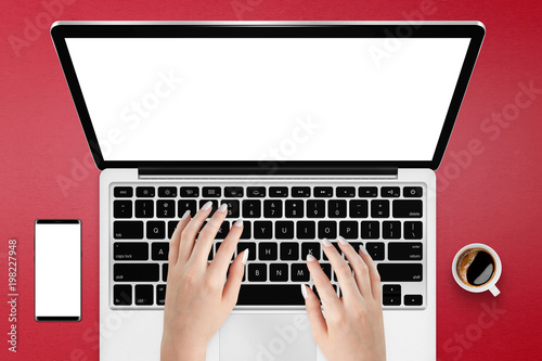 Female using laptop with isolated screen on red table surrounded with coffee and phone. Responsive mockup of laptop and smartphone
