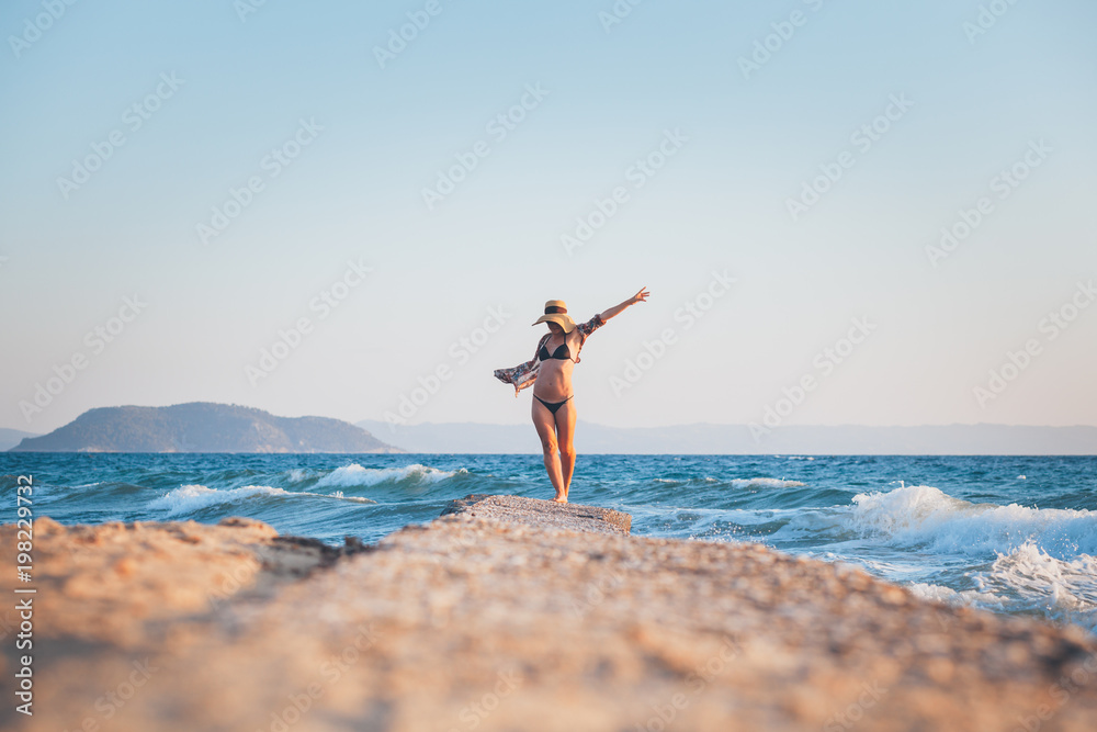 Happy young woman walking on the dock at the beach