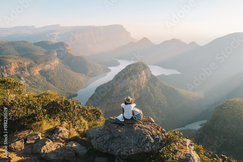Rear view of woman looking at view while sitting on mountain rock photo