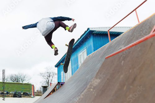 A skateboarder teenager in a hat does a trick with a jump on the ramp. A skateboarder is flying in the air © yanik88