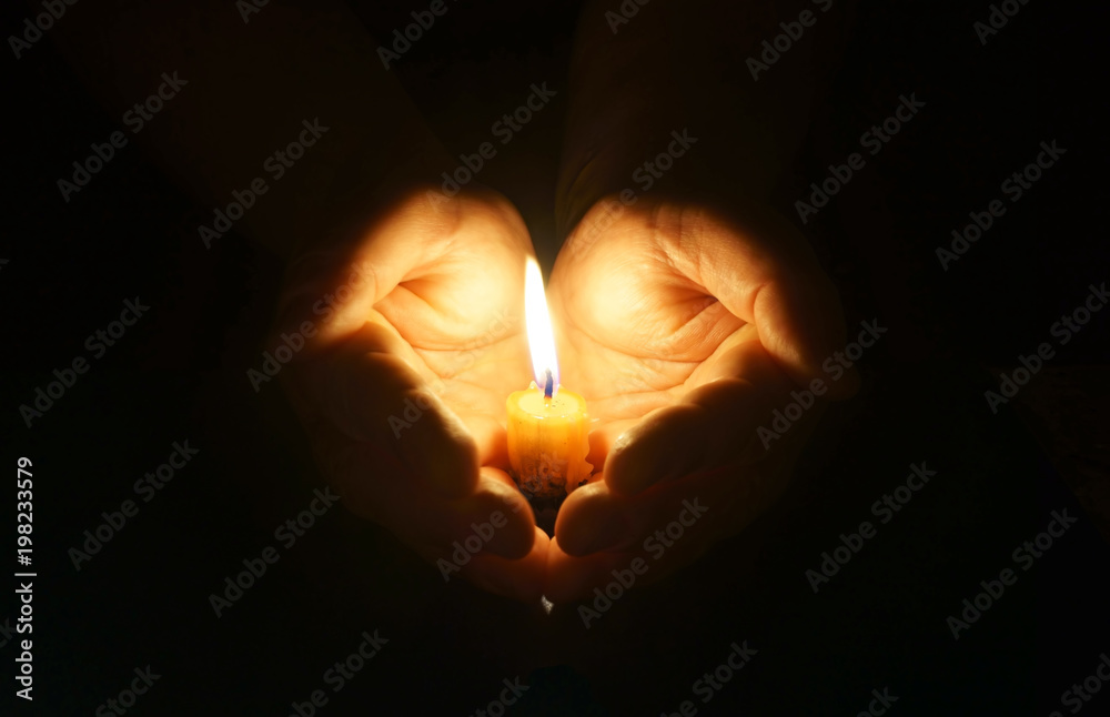 Cupped hands with burning candle.