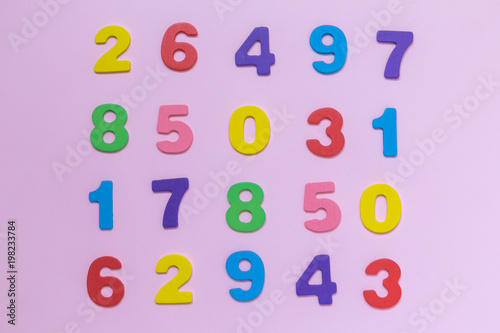 Multicolored wooden numbers texture on pastel rose background minimalistic concept.