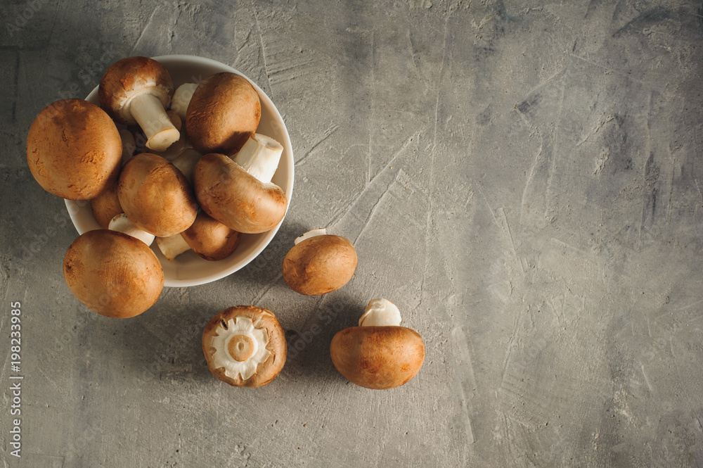 Obraz premium Royal champignons on a gray concrete background. Raw vegetarian food. Flat lay with place for text.