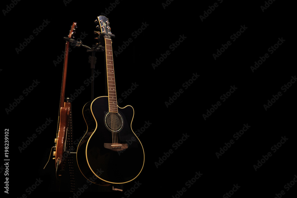 Acoustic guitar and electric guitar on the stage, on a black background