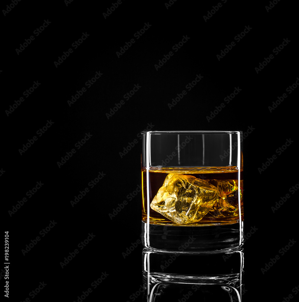 Whiskey glass with golden alcohol and ice cube Whiskey glass with golden alcohol and ice cube
